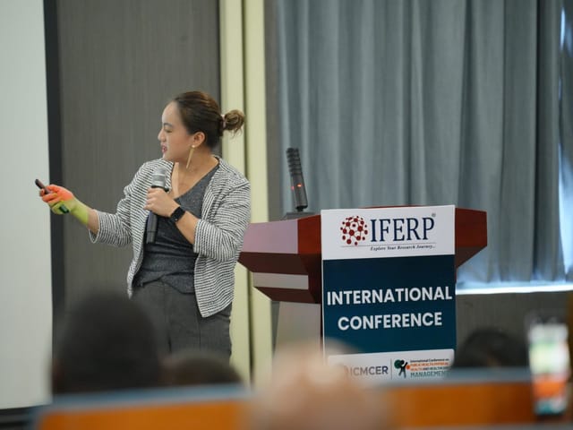 A presenting author speaking to the audience beside an IFERP lectern